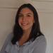 Luciana Leite has long dark hair and is wearing a light blue blouse. She is smiling at the camera.