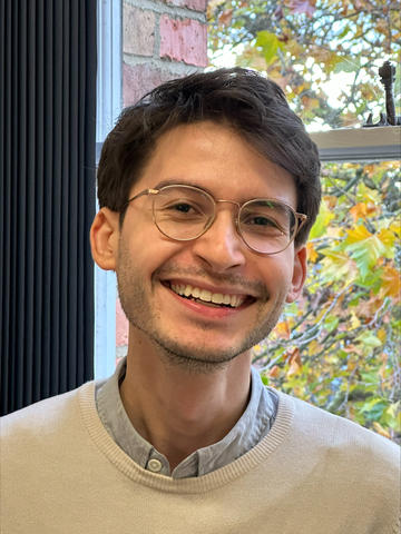 David is smiling at the camera wearing glasses