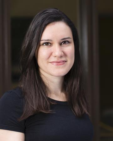 Dr Gabriela Pavarini has shoulder length dark hair, waring a black top smiling gently at the camera.