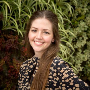 Ana Restrepo saenz  has long shoulder length hair wearing a floral top smiling directly at the camera.