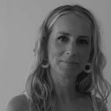 Lucy Olsen, has long shoulder length hair an smiling at the camera in a black and white photo.