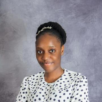 Temitope is smiling at the camera with her hair up in a bun and wearing a polka top.